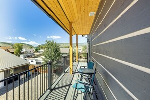 A balcony with a view of the surrounding area, including a building with a grey facade and a wooden deck.