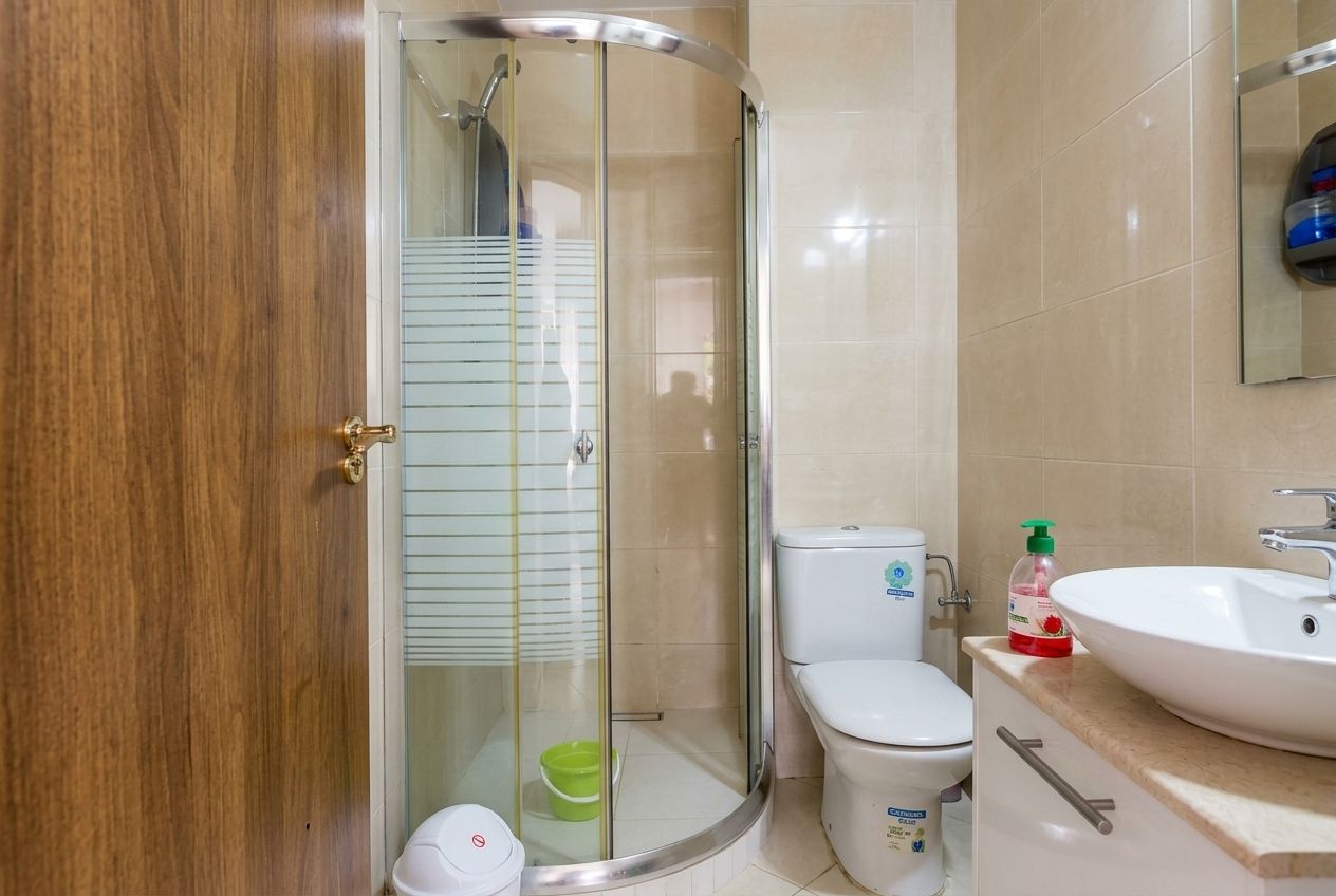 A bathroom with a glass shower enclosure, a toilet, and a sink.