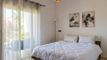 A bedroom with a bed, a floor lamp, and two paintings on the wall.