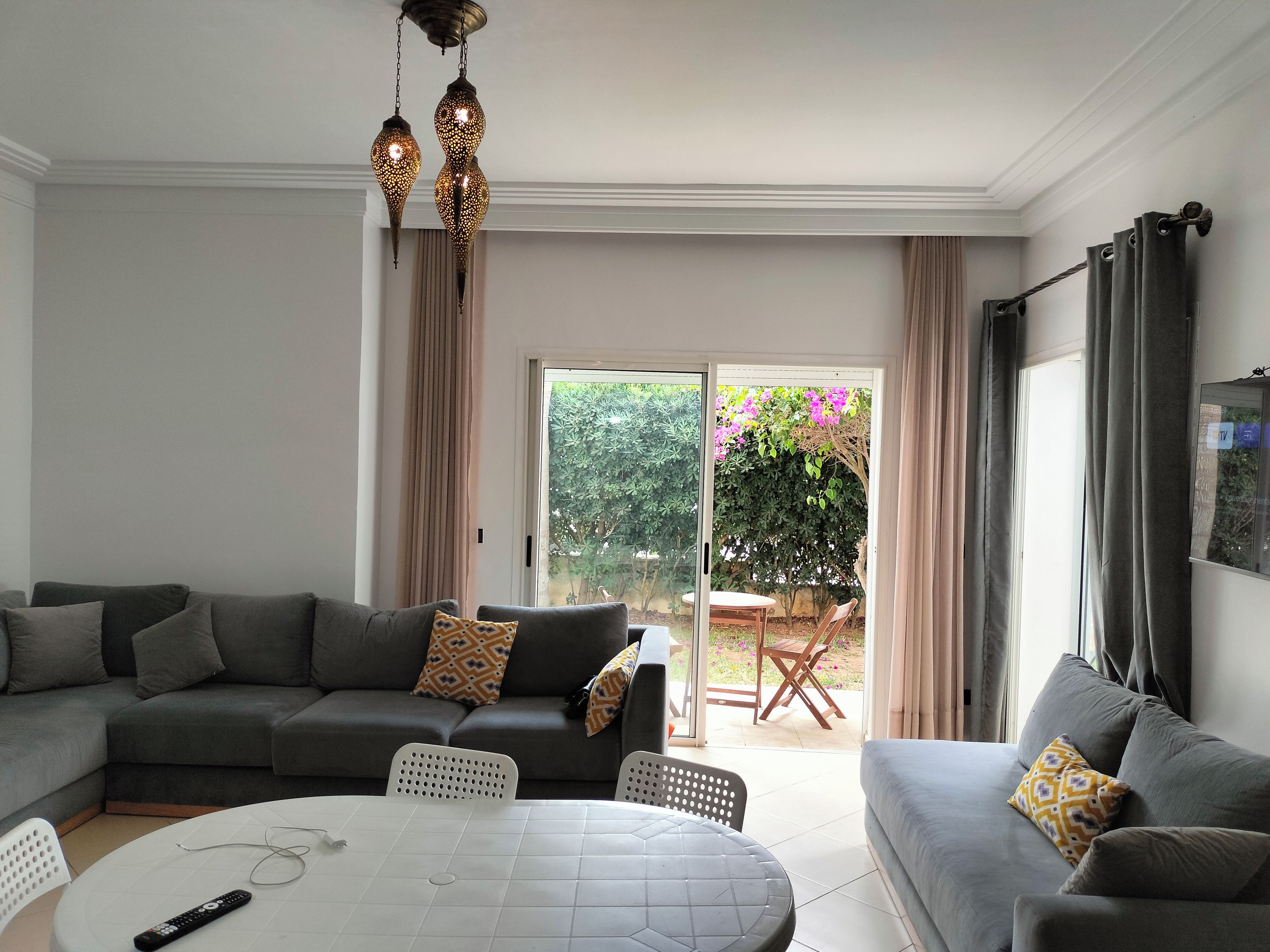 A living room with a sectional sofa, a round table, and a TV mounted on the wall.