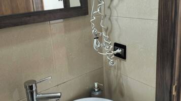 A bathroom with a white sink, a hairdryer mounted on the wall, and a mirror.