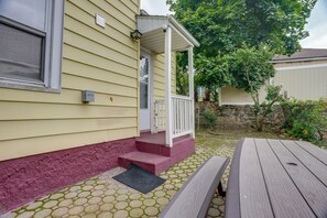 A house with a covered porch, a stone wall, and a wooden table. - Near Shops & Transit to Nyc! Yonkers Apt (Yonkers)