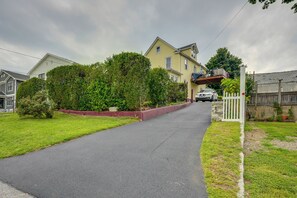 A residential street with houses on either side, a paved driveway, and a white picket fence. - Near Shops & Transit to Nyc! Yonkers Apt (Yonkers)
