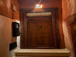A wooden door with intricate carvings and a metal grille, leading to a room with a tiled floor. - The Connected Riad: Remote Work in the Sun, a Giant Rooftop, & Professional Wi-Fi (Marrakech)