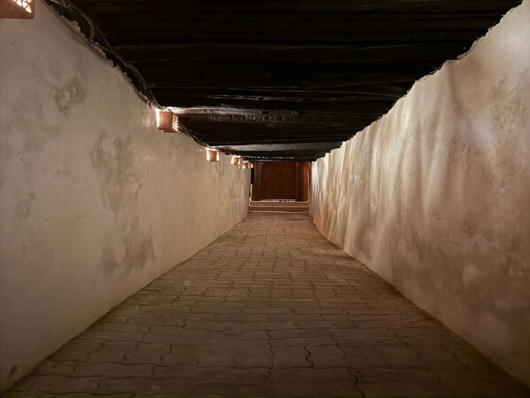 A narrow corridor with a brick floor and walls, leading to a wooden door at the end. - Vrbo Property (Marrakech)