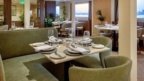 A restaurant with multiple tables set for dining, featuring a view of the cityscape. - MS Royal Serenade (Luxor)