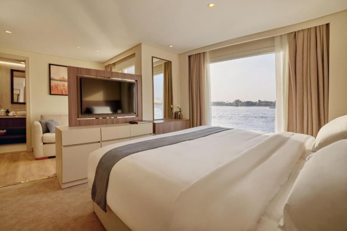 Habitación de hotel con una cama grande, televisión, escritorio y vista al agua.