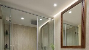 A modern bathroom with a glass shower enclosure, a white sink, and a wooden vanity. - MS Royal Serenade (Luxor)