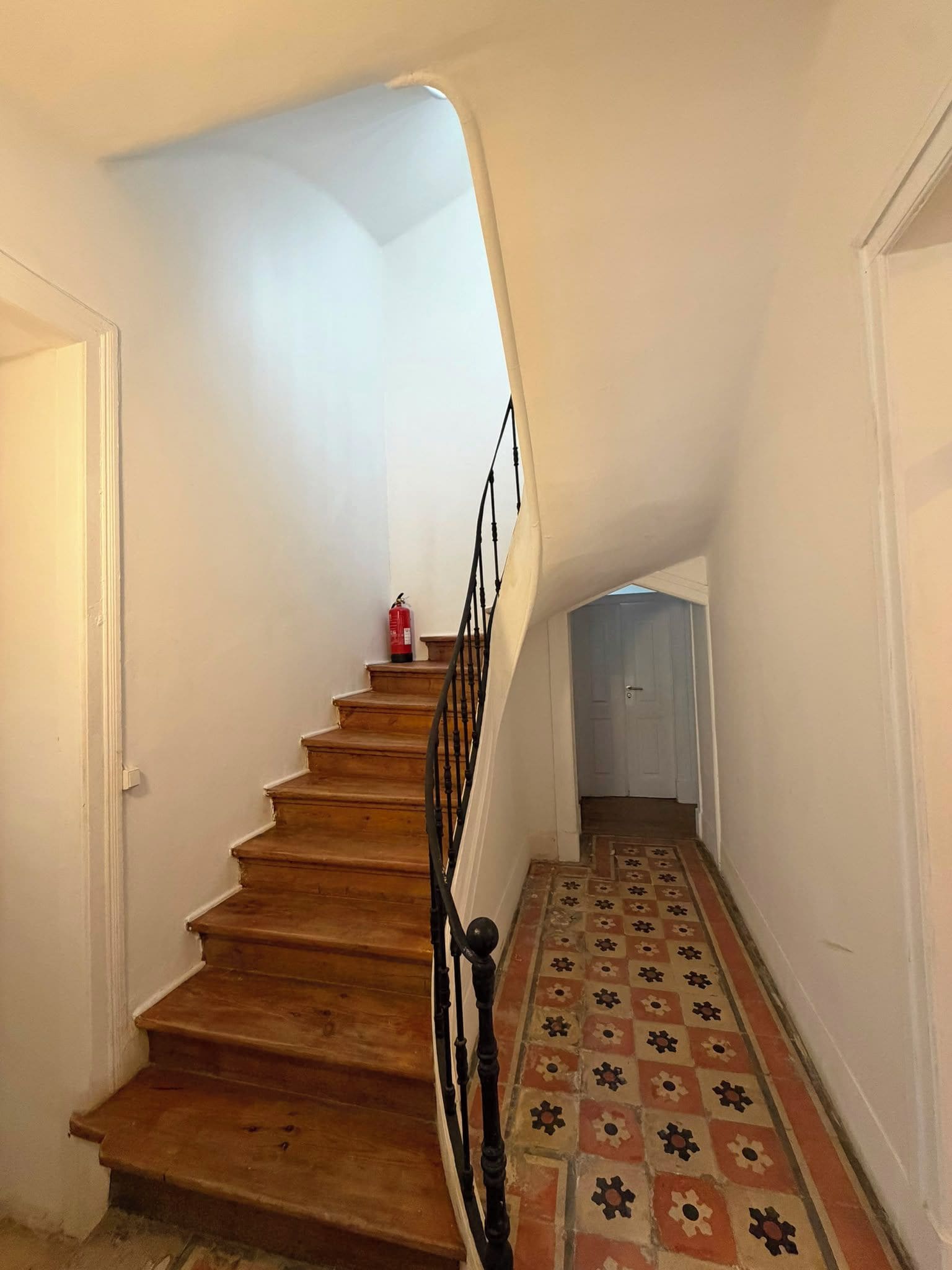 A wooden staircase with a black handrail leading to a landing.