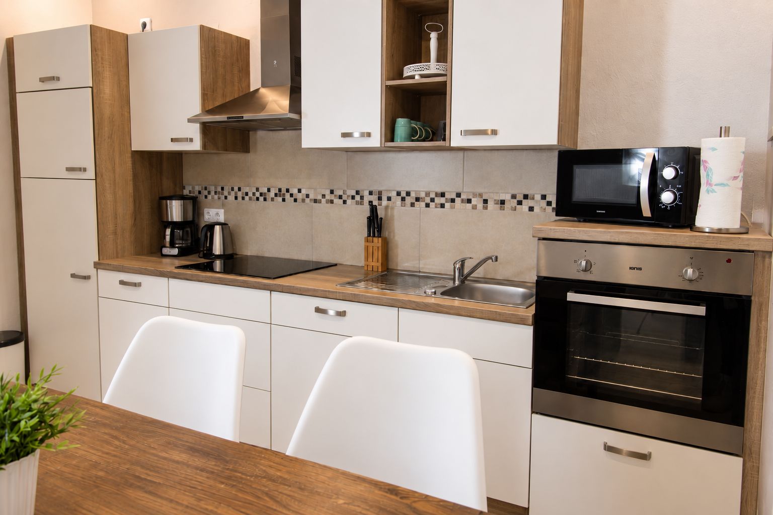 Een moderne keuken met een magnetron, oven, spoelbak en een koffiezetapparaat.
