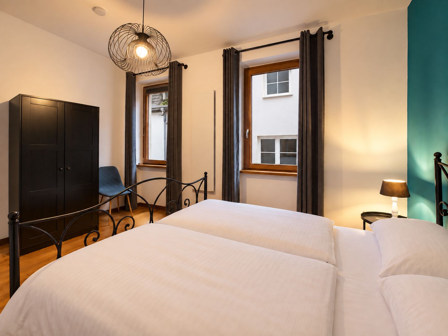 Een slaapkamer met een bed, een stoel, een kledingkast en een raam met gordijnen.