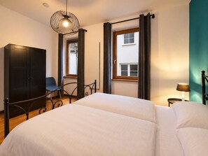 Een slaapkamer met een bed, een stoel, een kledingkast en een raam met gordijnen.