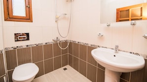 Un baño con inodoro, lavamanos, ducha y espejo.