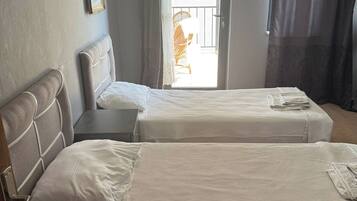 Ein Hotelzimmer mit zwei Betten, einer Tür, die auf einen Balkon führt, und einem gerahmten Bild an der Wand.