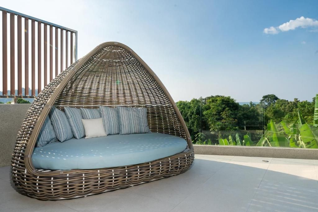 A wicker daybed with a view of greenery and a railing.