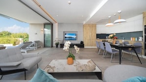 Een moderne woonkamer met een bank, een salontafel en een eettafel met stoelen.