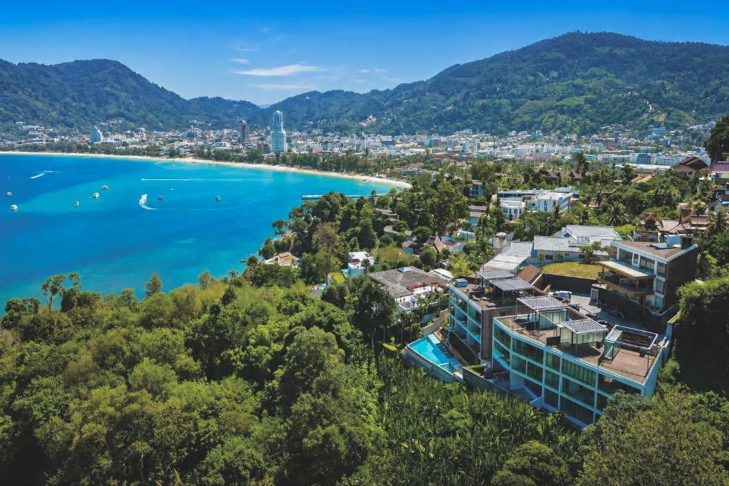 A coastal town with a clear view of the ocean, buildings, and a hilly landscape.