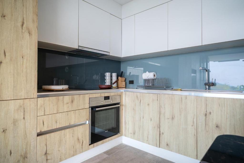 A modern kitchen with wooden cabinetry, a built-in oven, and a large window providing a view.