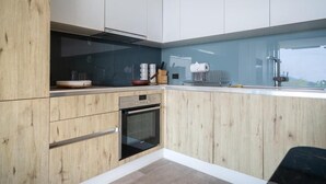 Een moderne keuken met houten kasten, een inbouwoven en een groot raam met uitzicht.