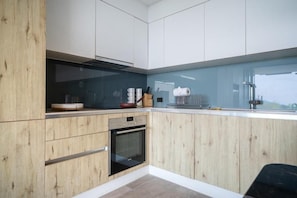 Uma cozinha moderna com armários de madeira, forno embutido e uma grande janela com vista.