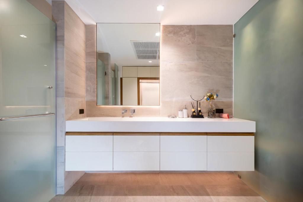 A modern bathroom with a large mirror, a white vanity, and a glass shower enclosure.
