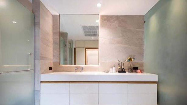 Een moderne badkamer met een grote spiegel, een witte wastafel en een douchecabine met glazen wanden.