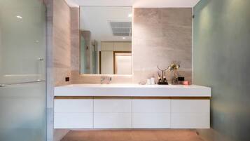A modern bathroom with a large mirror, a white vanity, and a glass shower enclosure.