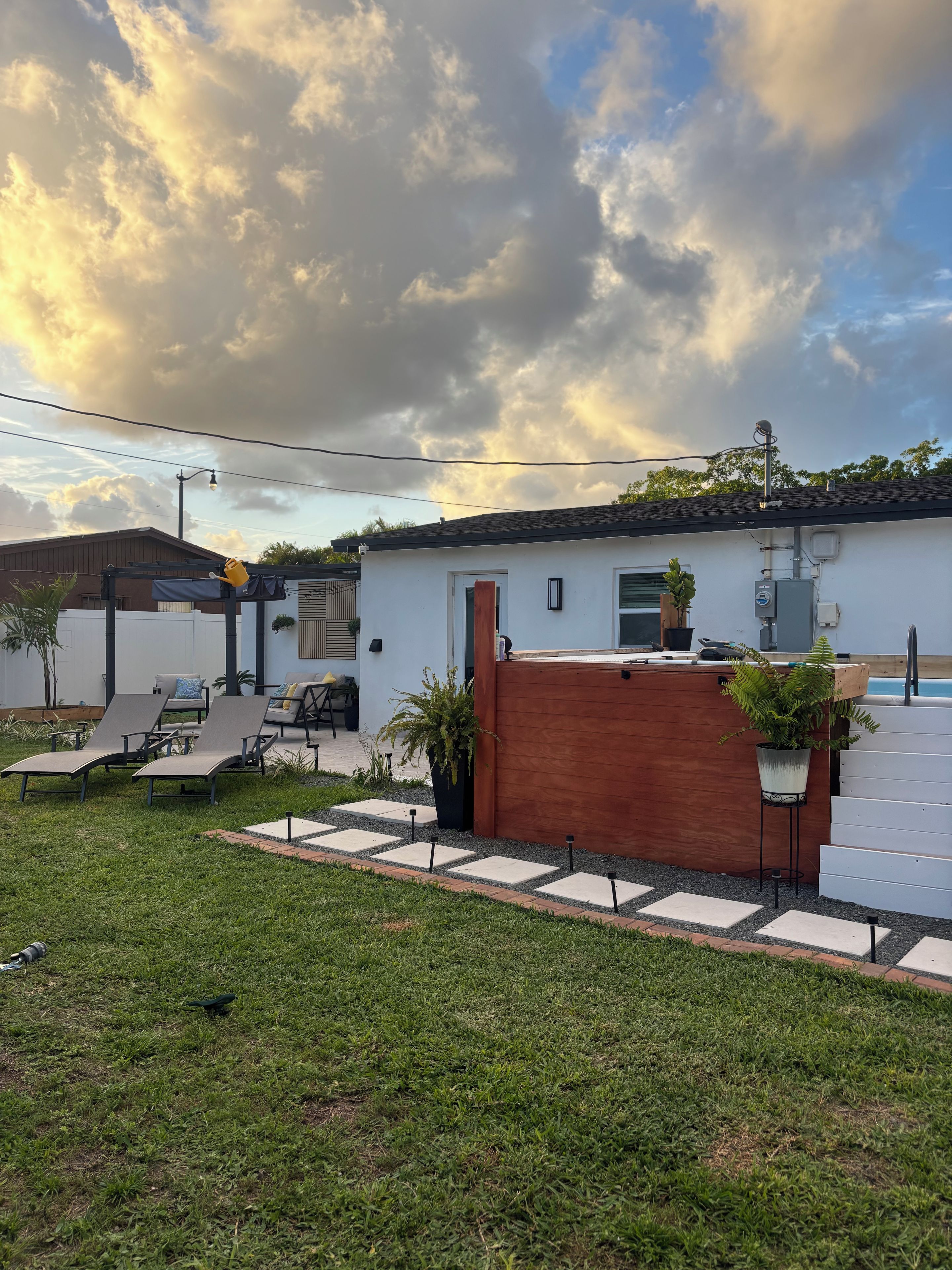 Un patio trasero residencial con piscina, sillones de descanso y una terraza de madera.
