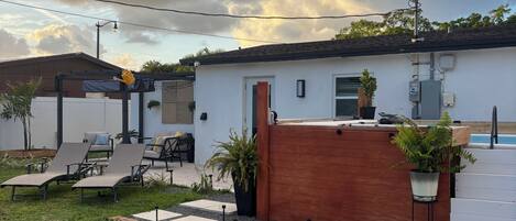 Un patio trasero residencial con piscina, sillones de descanso y una terraza de madera.