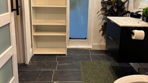 Et badeværelse med toilet, vask og hylder.