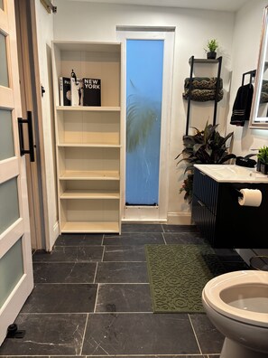 Ein Badezimmer mit Toilette, Waschbecken und Regalen.