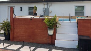 En boligejendom med swimmingpool, træterrasse og have.