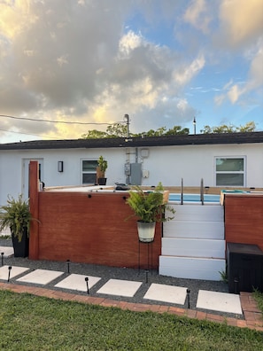 Ein Wohnhaus mit Schwimmbad, einer Holzterrasse und einem Garten.