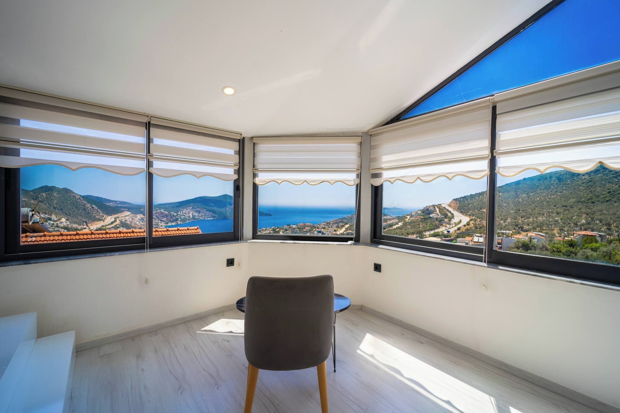 Una habitación con vista a un paisaje costero, una silla y una mesa.