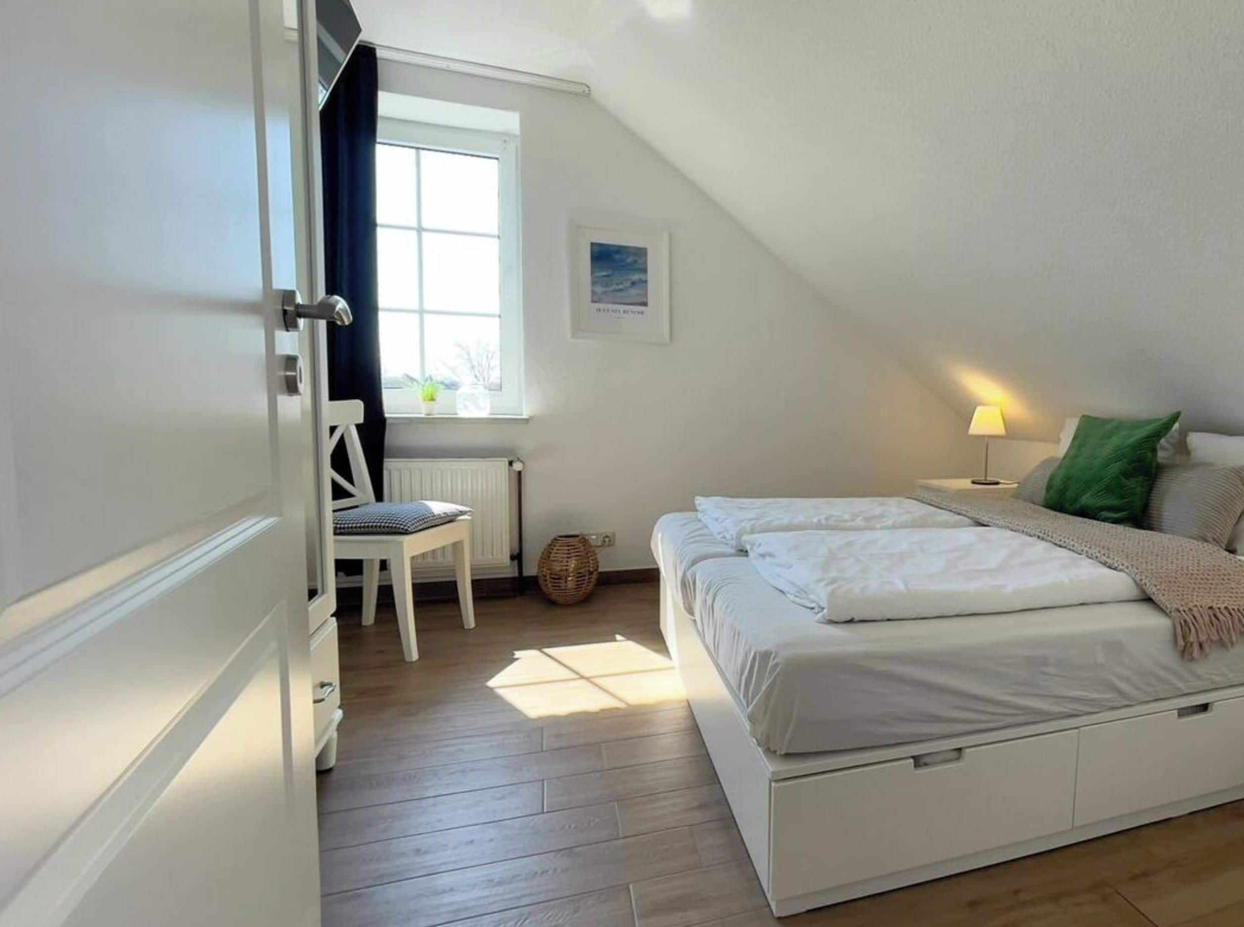 Een slaapkamer met een bed, een stoel, een raam en een lamp.