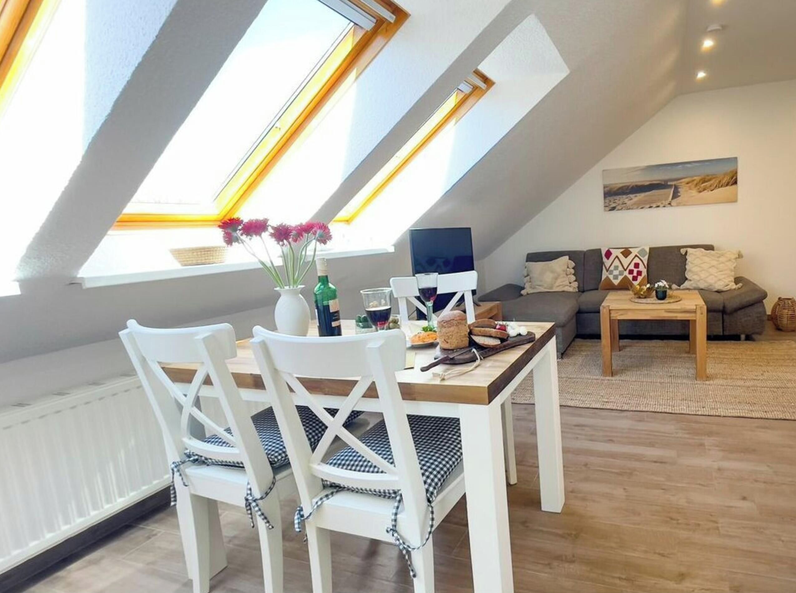 Un coin repas avec une table et des chaises, une fenêtre donnant sur un beau paysage, et un espace de détente avec un canapé et un tableau.