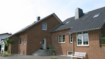 A brick building with a front entrance, steps leading up to the door, and a bench outside.