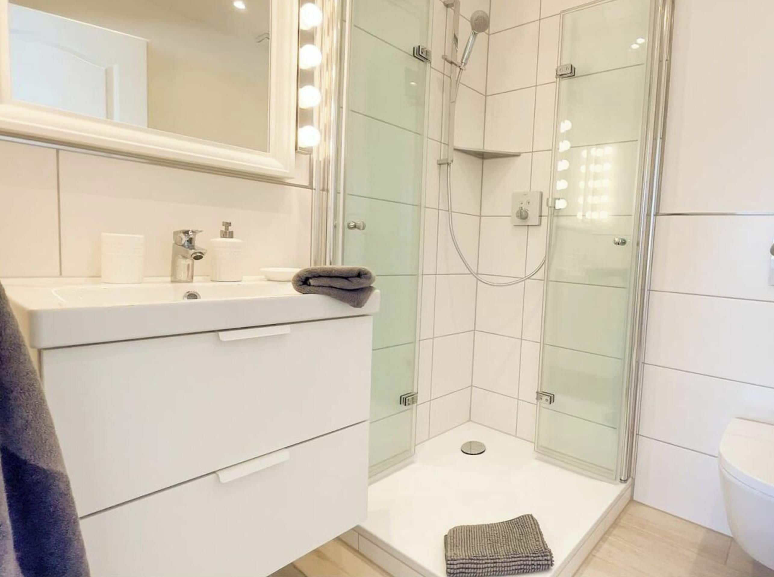 Une salle de bain moderne avec une douche à parois de verre, un meuble-lavabo avec un miroir et des toilettes.