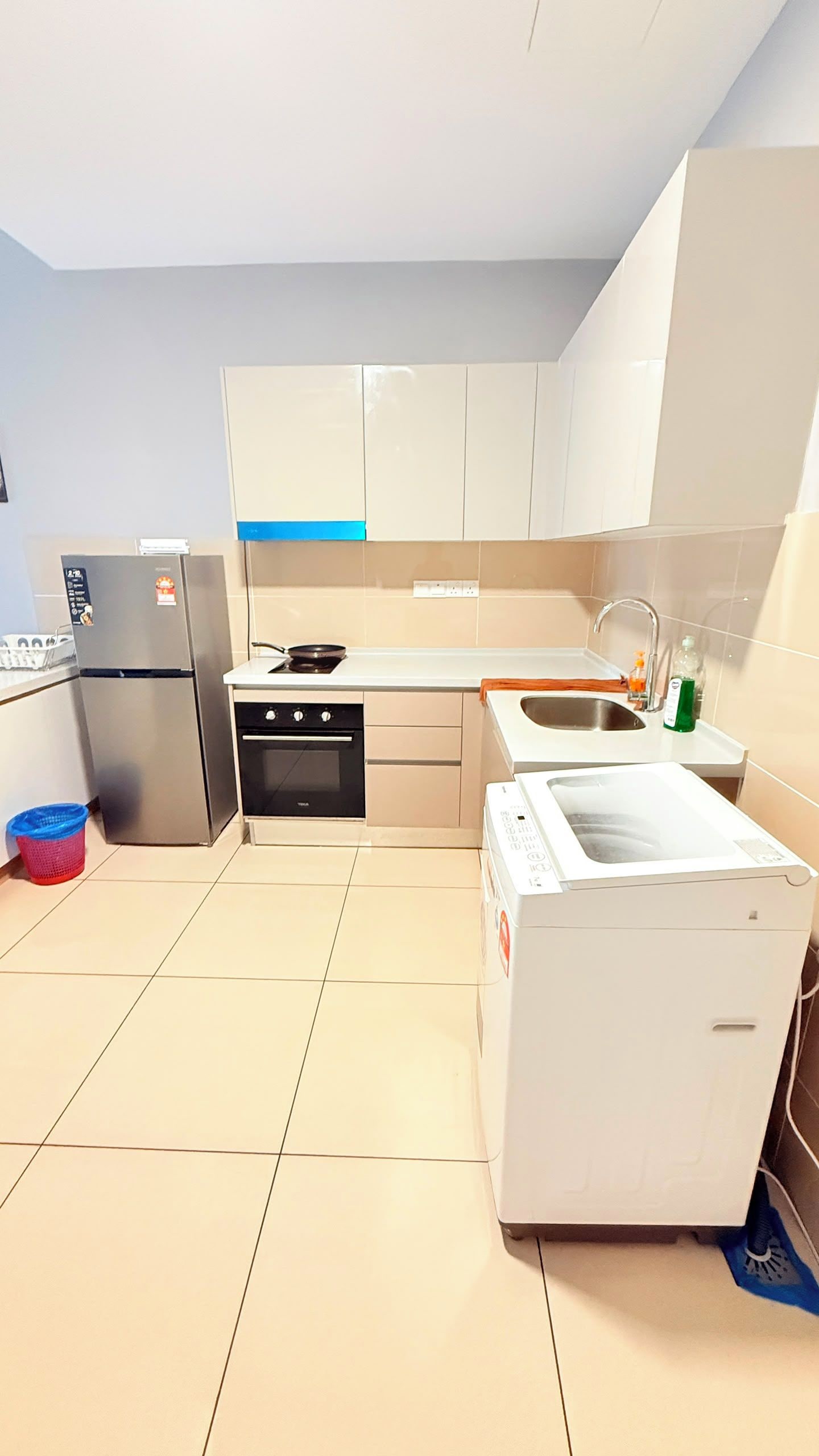 Una cocina moderna con armarios blancos, un refrigerador de acero inoxidable, un horno empotrado, un microondas y un fregadero.