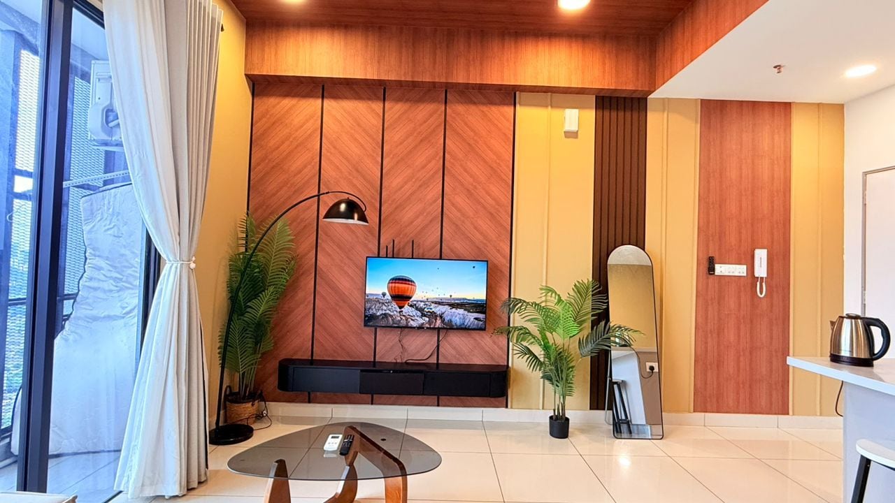 Una sala de estar moderna con un televisor de pantalla plana montado en una pared de madera, una mesa de centro de vidrio y dos plantas en macetas.