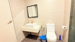 A small bathroom with a toilet, sink, and mirror. - Trion KL Premier Residence (Kuala Lumpur)