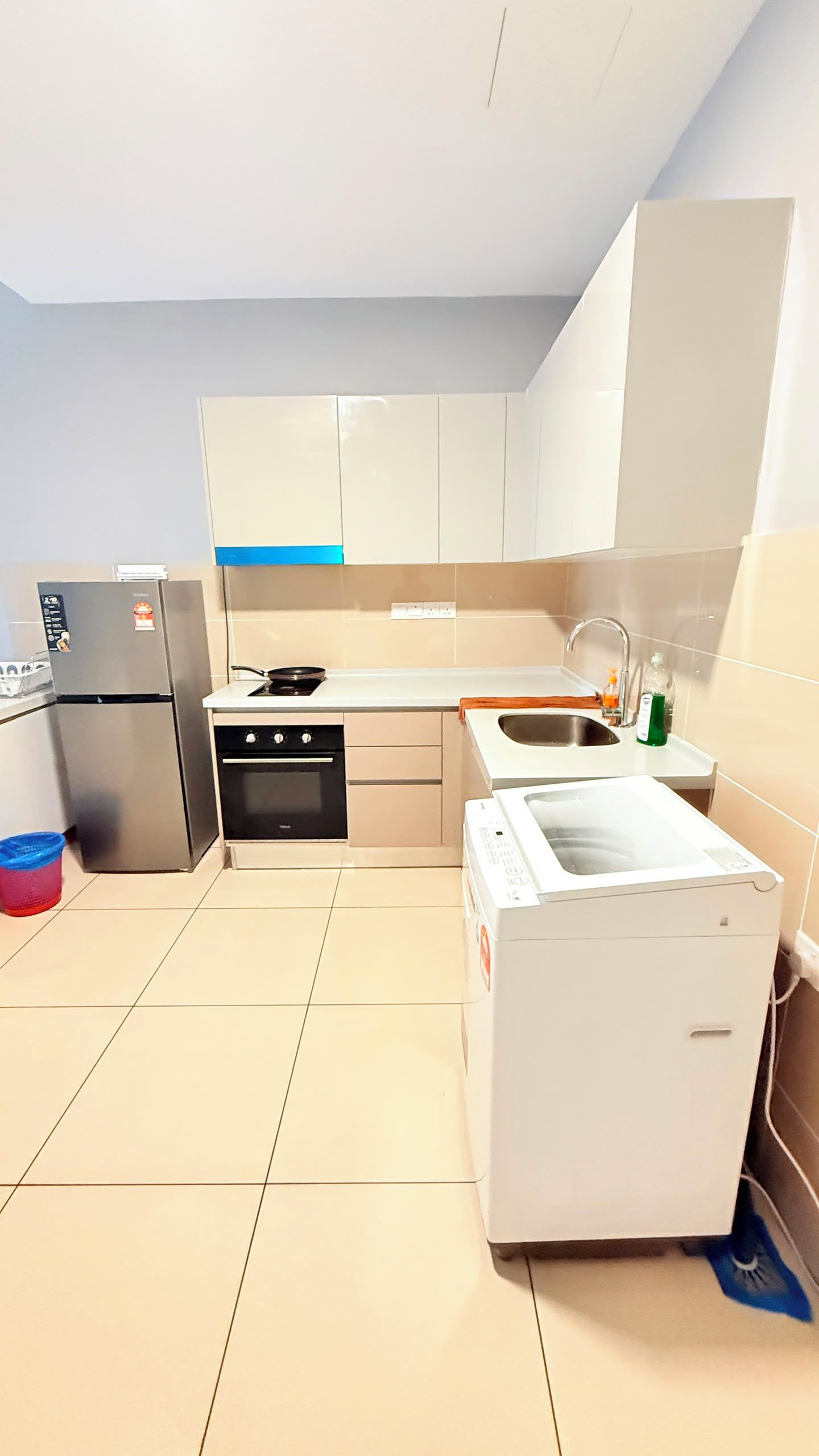 A compact kitchen with a refrigerator, stove, sink, and a washing machine.