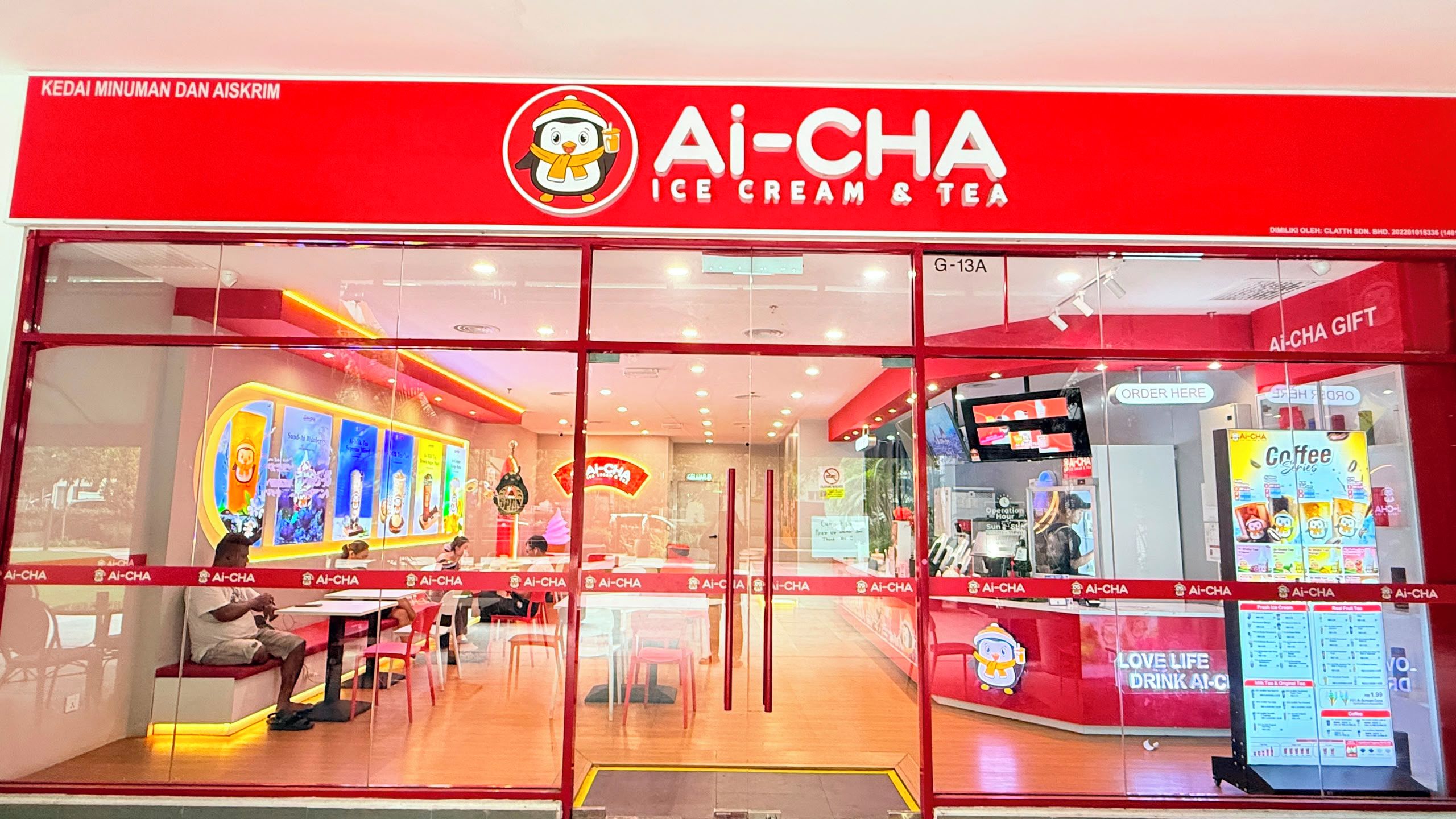 A brightly lit Ai-CHA ice cream and tea shop with a red exterior and glass doors.
