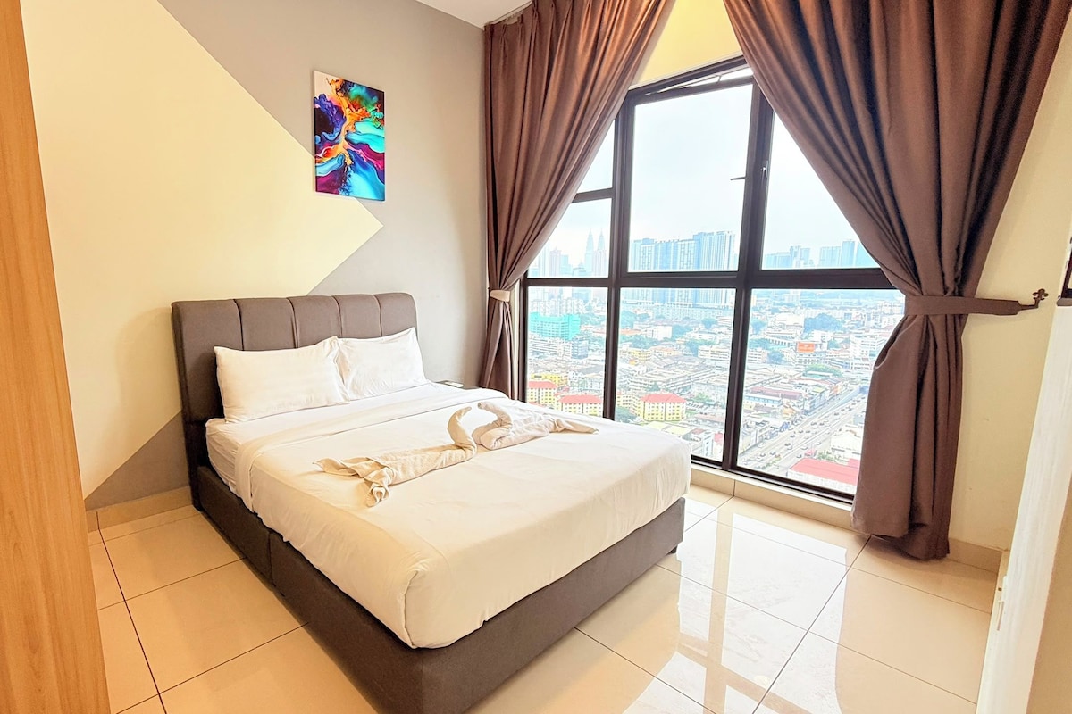 A hotel room with a large bed, a city view, and a painting on the wall.