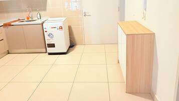 A kitchen with a washing machine, a sink, and cabinets.