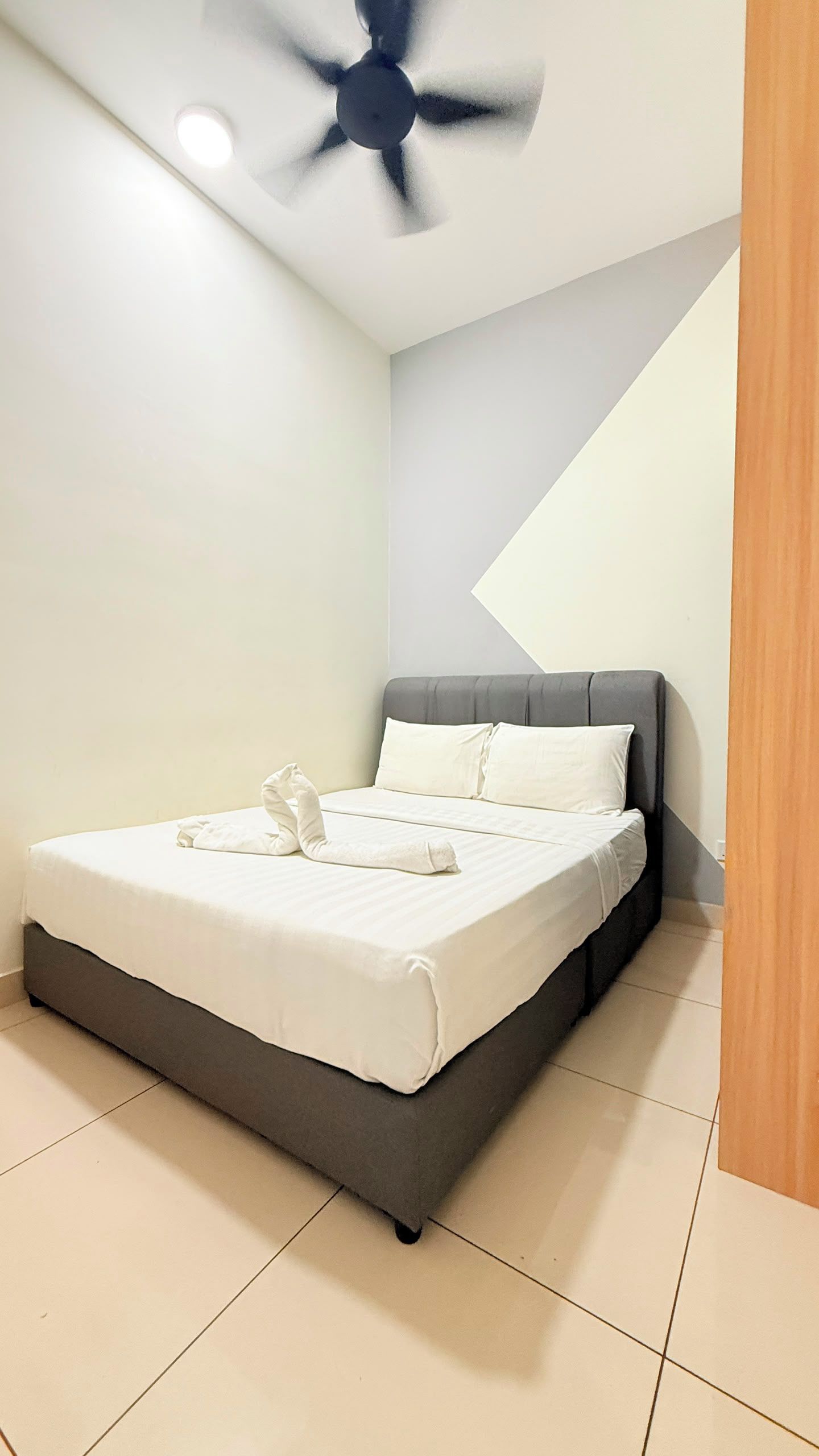 Ein Schlafzimmer mit Bett, Deckenventilator und einer Eckwandgestaltung.