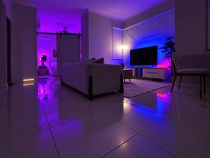 Ein modernes Wohnzimmer mit einer Couch, einem Fernseher und einer Pflanze.