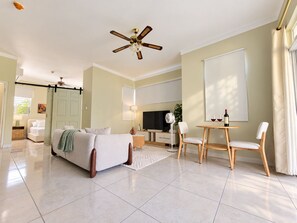 Een ruime slaapkamer met een groot bed, een plafondventilator en een televisie.