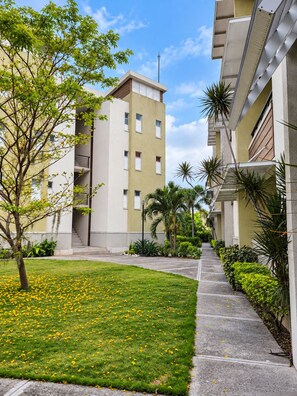 A residential building with a central courtyard, surrounded by greenery and a clear sky. - Serene Smart Suite ● Devon House Ice-Cream ● Gated ● Smart Stay (Kingston)