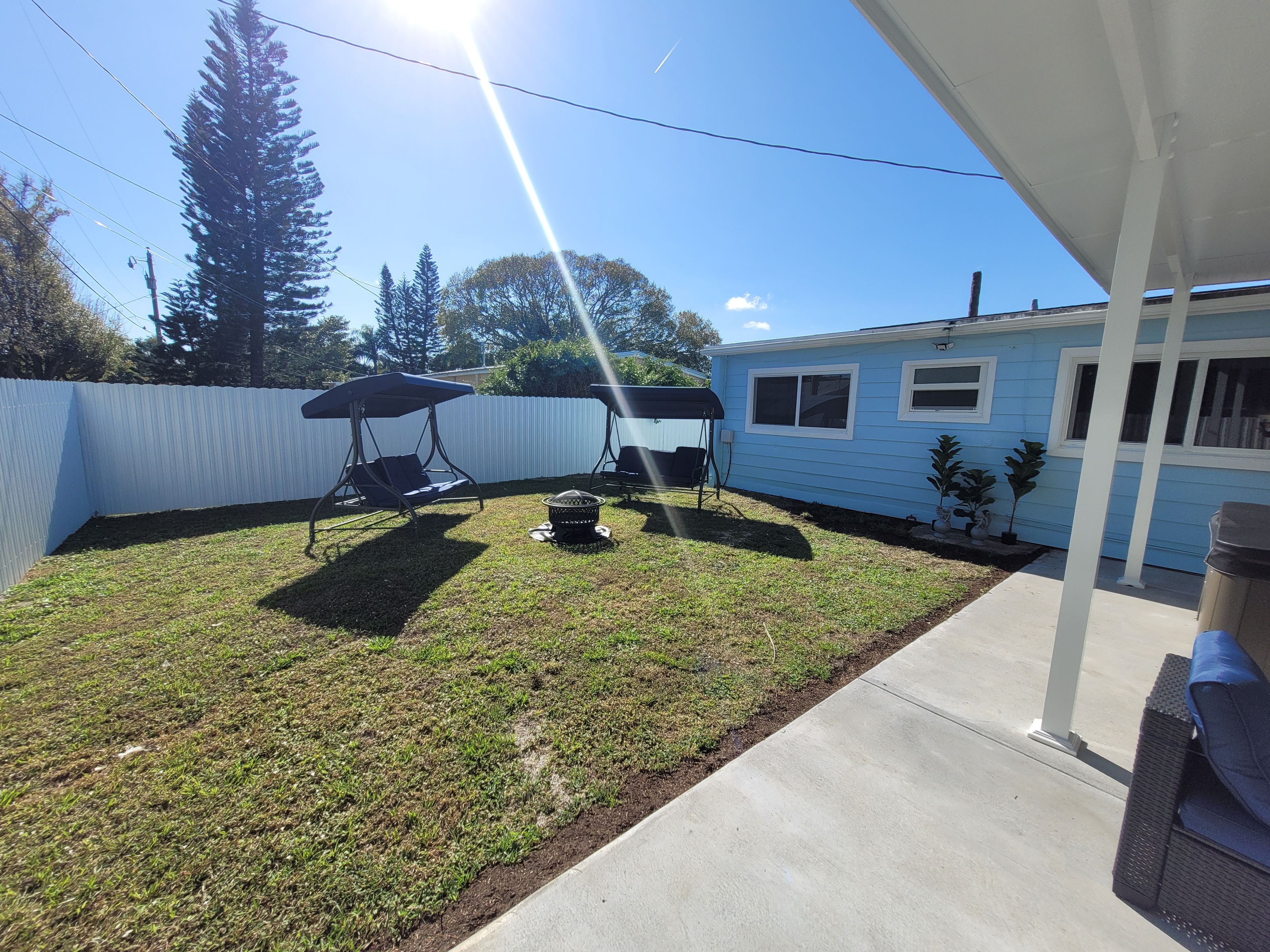 A backyard with a swing set, grill, and a small shed.